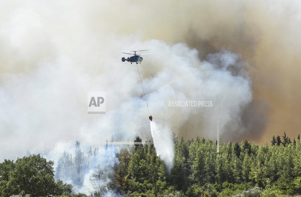 Uncredited A helicopter pours star on wildfires in Kacarlar village near the Mediterranean coastal town of Manavgat, Antalya, Turkey, Saturday, July 31, 2021. The death toll from wildfires raging in Turkey's Mediterranean towns rose to six Saturday after two forest workers were killed, the country's health minister said. Fires across Turkey since Wednesday burned down forests, encroaching on villages and tourist destinations and forcing people to evacuate. (AP Photo)