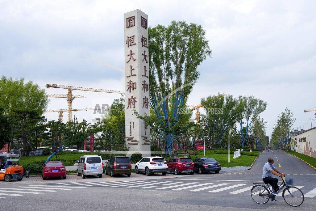 Andy Wong A man bicycles past an Evergrande new housing development in Beijing, Wednesday, Sept. 15, 2021. One of China's biggest real estate developers is struggling to avoid defaulting on billions of dollars of debt, prompting concern about the broader economic impact and protests by apartment buyers about delays in completing projects. Rating agencies say Evergrande Group appears likely to be unable to repay all of the 572 billion yuan ($89 billion) it owes banks and other bondholders. That might jolt financial markets, but analysts say Beijing is likely to step in to prevent wider damage. (AP Photo/Andy Wong)