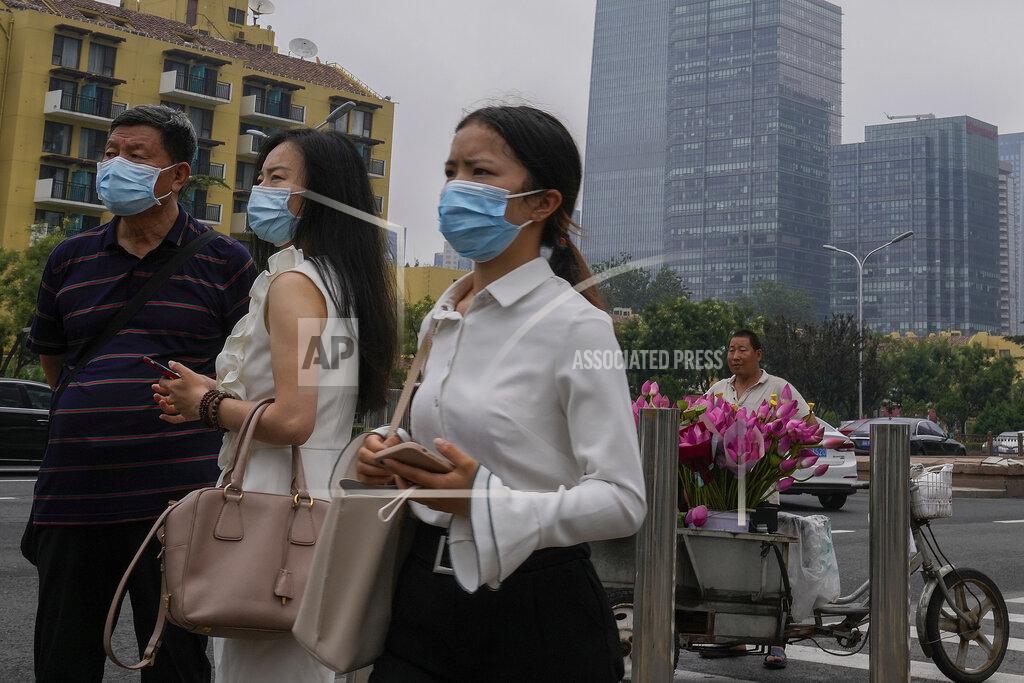 Andy Wong People wearing face masks to help curb the spread of the coronavirus stand watch near a vendor selling flowers outside a subway station in Beijing, Thursday, July 22, 2021. A senior Chinese health official says China cannot accept the World Health Organization's plan for the second phase of a study into the origins of COVID-19. (AP Photo/Andy Wong)