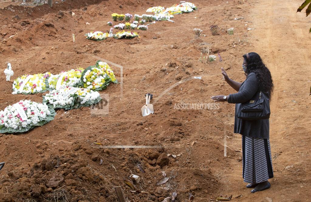 Andre Penner Vera Lucia Souza prays at the gravesite of her 47-year-old brother Paulo Roberto da Silva, who died of COVID-19, during his burial at the Sao Luiz cemetery in Sao Paulo, Brazil, Thursday, June 4, 2020. (AP Photo/Andre Penner)