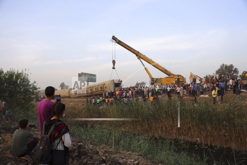 Fadel Dawood A crane is used to lift a part of a passenger train that derailed injuring some 100 people, near Banha, Qalyubia province, Egypt, Sunday, April 18, 2021. At least eight train wagons ran off the railway, the provincial governor's office said in a statement. (AP Photo/Fadel Dawood)