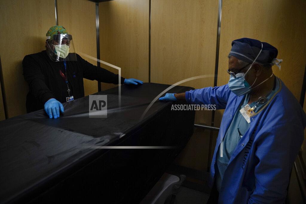 Jae C. Hong FILE - In this Jan. 9, 2021, file photo, transporters Miguel Lopez, right, Noe Meza move a body of a COVID-19 patient to a morgue at Providence Holy Cross Medical Center in the Mission Hills section of Los Angeles. The U.S. death toll from COVID-19 has topped 500,000 — a number so staggering that a top health researchers says it is hard to imagine an American who hasn't lost a relative or doesn't know someone who died. (AP Photo/Jae C. Hong, File)