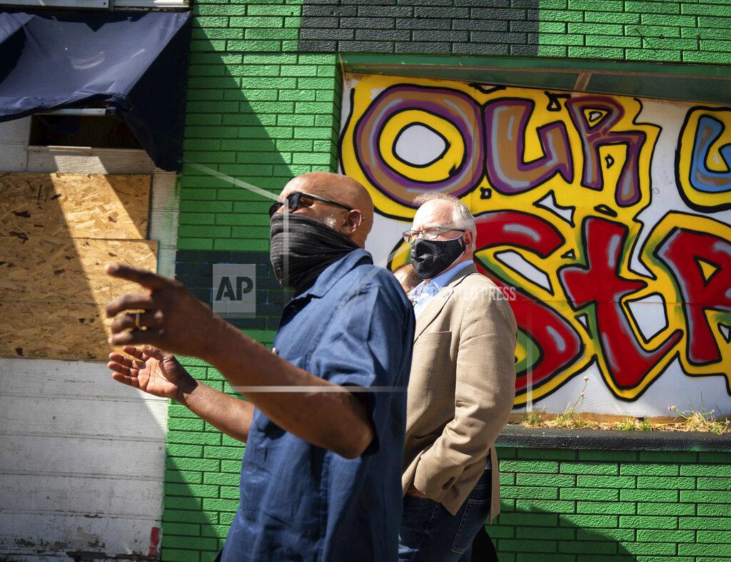 Glen Stubbe CORRECTS SPELLING TO SEITU, INSTEAD OF SEITO - Minnesota Gov. Tim Walz, right, takes a walking tour of some of the artworks commissioned by Springboard for the Arts along University Avenue in St. Paul, Minn., Monday, June 8, 2020. With him is artist Seitu Jones. (Glen Stubbe/Star Tribune via AP, Pool)