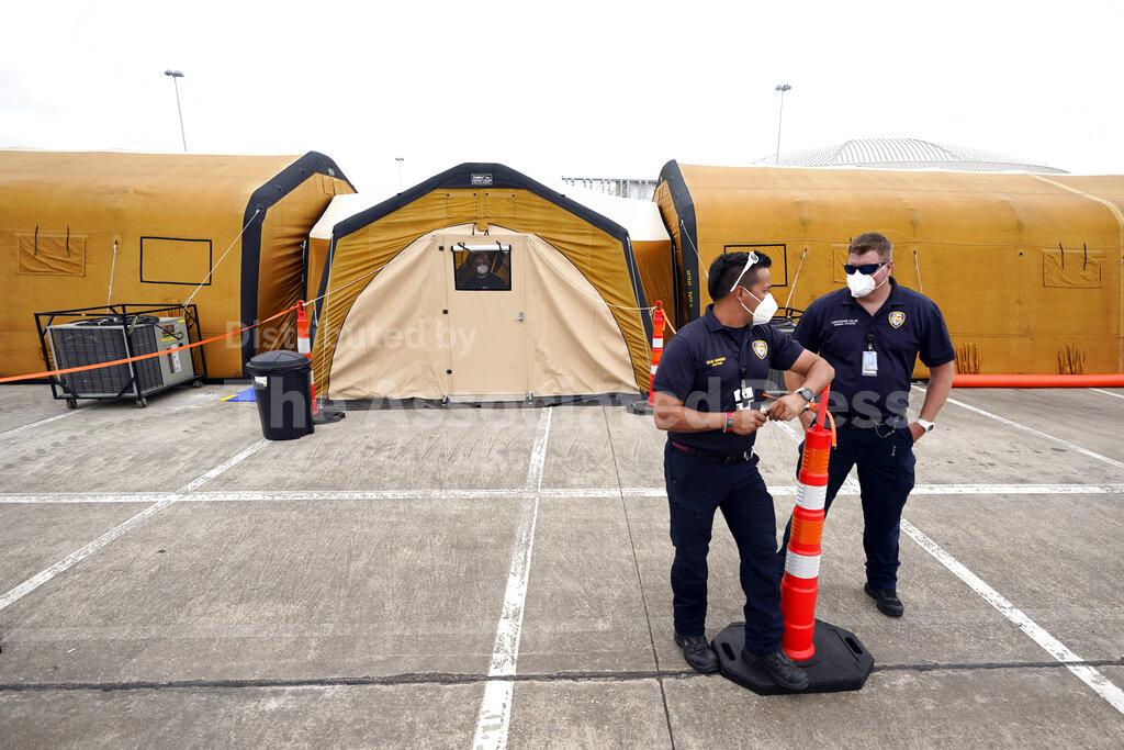 Beau Moreno, left, and Chris Cullen, both with Houston Fire Department, wait outside the intensive care unit during a tour of the new Harris County Non-Congregate Medical Shelter at NRG Park Saturday, April 11, 2020, in Houston. The new temporary setup will have 250 beds initially with a capacity of 2000 beds, if needed, to help relieve pressure on the hospital system from COVID-19 patients. Activation is not intended at this time. (AP Photo/David J. Phillip)