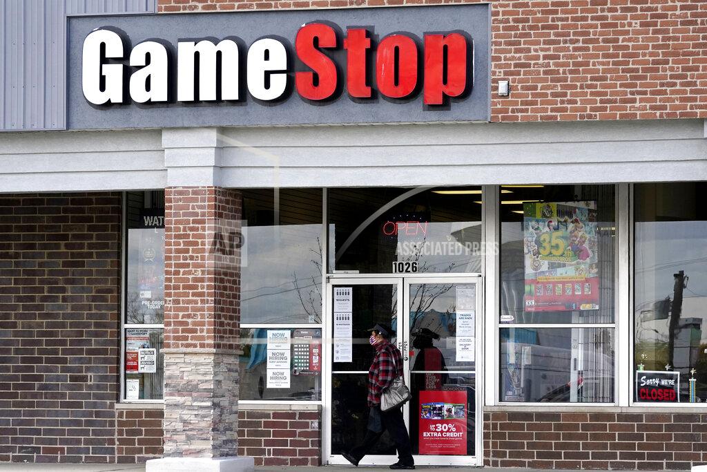 FILE - In this Oct. 15, 2020 file photo, a woman wears a face mask as she walks past a GameStop store in Des Plaines, Ill. Two hedge funds are bowing out of their short positions on the money-losing video game retailer. Citron Research’s Andrew Left said in a video posted on YouTube that his company is going to become more judicious in shorting stocks. Melvin Capital is also exiting GameStop, with manager Gabe Plotkin telling CNBC that the hedge fund was taking a significant loss. (AP Photo/Nam Y. Huh, File)