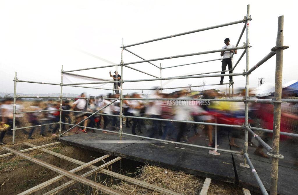 Fernando Vergara People stream through a gate before the Venezuela Aid Live concert on the Colombian side of Tienditas International Bridge on the outskirts of Cucuta, Colombia, on the border with Venezuela, Friday, Feb. 22, 2019. Venezuela's power struggle is set to convert into a battle of the bands Friday when musicians demanding Nicolas Maduro allow in humanitarian aid and those supporting the embattled leader's refusal sing in rival concerts being held at both sides of a border bridge where tons of donated food and medicine are being stored. (AP Photo/Fernando Vergara)