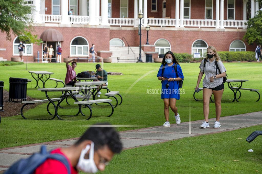 Alyssa Pointer FILE - In this Aug. 21, 2020, file photo, Georgia College and State University freshmen Ashlynn Anglin, right, and Meghan Murphy, second from right, wear face masks as they talk while walking through the campus in Milledgeville, Ga. As more and more schools and businesses around the country get the OK to reopen, some college towns are moving in the opposite direction because of too much partying and too many COVID-19 infections among students. (Alyssa Pointer/Atlanta Journal-Constitution via AP, File)