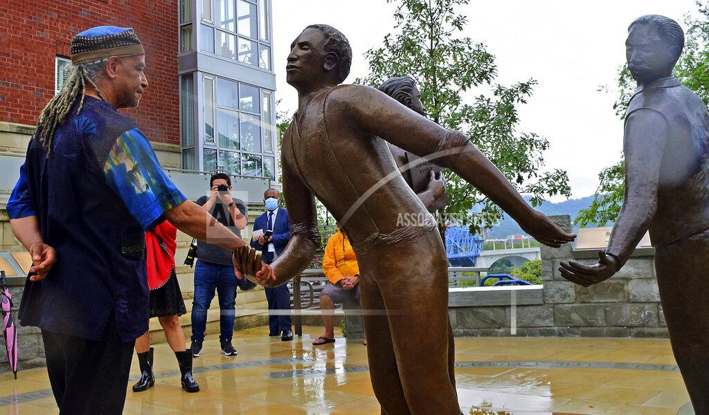 Robin Rudd Sculptor Jerome Meadows shakes the hand of his figure of Ed Johnson during its dedication at a memorial at the south side of the Walnut Street Bridge in Chattanooga, Tenn., on Sunday, Sept. 19, 2021. The two other figures are those of Noah Parden and Styles Hutchens, two African-American attorneys from Chattanooga, who provided a courageous and successful defense for Johnson, who on March 19, 1906, was mob-lynched from the second span of the Walnut Street Bridge. (Robin Rudd/Chattanooga Times Free Press via AP)
