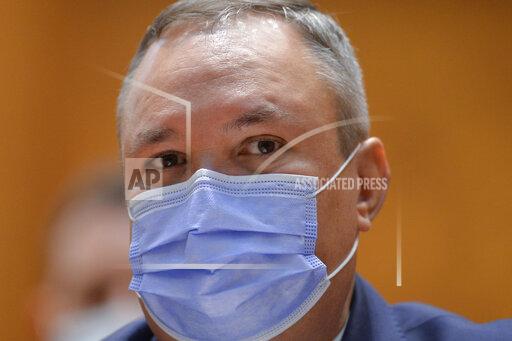 Romanian Prime Minister designate Nicolae Ciuca wears a mask before a parliament vote on his government team in Bucharest, Romania, Thursday, Nov. 25, 2021. Romanian lawmakers voted in favor of a new coalition government led by a Liberal former army general, which could usher in an end to a months-long political crisis in the Eastern European nation.(AP Photo/Alexandru Dobre)