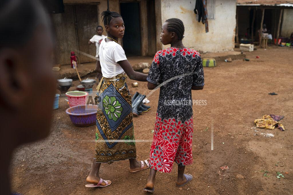 Marie walks with a friend on a street in Komao village, on the outskirts of Koidu, district of Kono, Sierra Leone, Sunday, Nov. 22, 2020. A man, in his mid-20s, first caught a glimpse of Marie as she ran with her friends past his house near the village primary school. Soon after, he proposed to the fifth-grader. “I’m going to school now. I don’t want to get married and stay in the house,” she told him. But the pressures of a global pandemic on this remote corner of Sierra Leone were greater than the wishes of a schoolgirl. (AP Photo/Leo Correa)