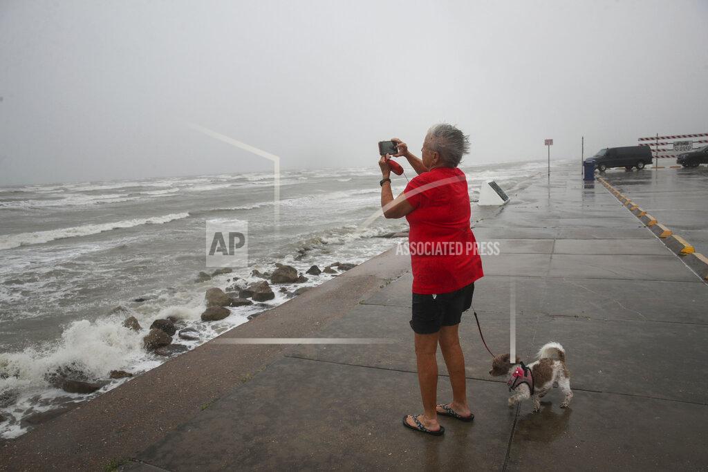 Jon Shapley Cheri Daigle, a retired teache, takes a photo as Tropical Storm Nicholas approaches the Texas coast Monday, Sept. 13, 2021, along the seawall in Galveston, Texas. (Jon Shapley/Houston Chronicle via AP)