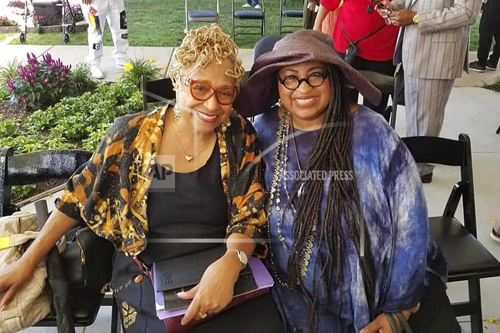 Uncredited In this 2019 photo provided by Marsha Battle Philpot, Philpot, right, widely known by her moniker Marsha Music and Brenda Perryman pose for a photo at the groundbreaking ceremony for the Motown Museum expansion in Detroit. As the coronavirus tightened its grip across the country, it is cutting a particularly devastating swath through an already vulnerable population, black Americans. The coronavirus deaths in Detroit include educator and playwright Perryman and Gloria Smith, who was a staple at the city’s African World Festival and died within a week of her husband. (Marsha Battle Philpot via AP)