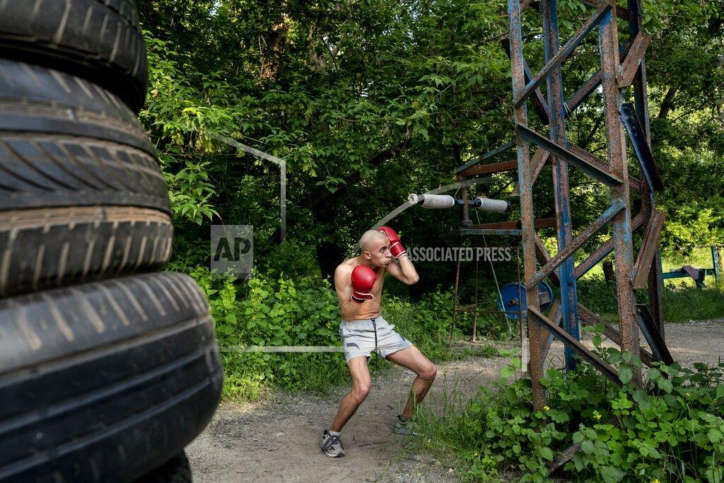 In this photo taken on Saturday, June 6, 2020, a man trains to box in the outdoors gym on the Dolobetskiy island on the Dnipro River in Kyiv, Ukraine. Relishing an opportunity to do exercise after a long lockdown, hundreds of Kyiv residents flock to an improvised outdoor workout on an island facing the Ukrainian capital. The Kachalka gym on the Dolobetskiy island on the Dnipro river has enjoyed broad popularity ever since it opened in 1966. (AP Photo/Evgeniy Maloletka)