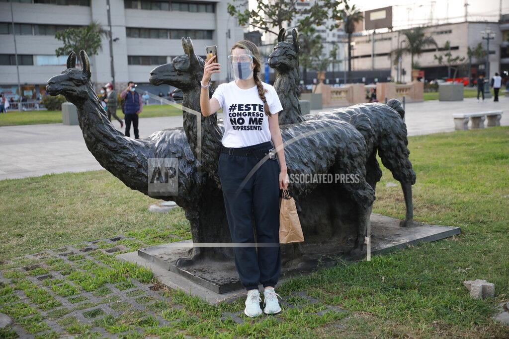 Rodrigo Abd A woman, wearing a T-shirt with a message that reads in Spanish: "This Congress does not represent me," takes a selfies leaning on the llamas statue outside the Justice Palace where people who are refusing to recognize the new government gathered to protest, in Lima, Peru, Wednesday, Nov. 11, 2020. On Tuesday, Peru swore in Manuel Merino as president, after Peru’s legislature booted President Martin Vizcarra from office on Monday. (AP Photo/Rodrigo Abd)