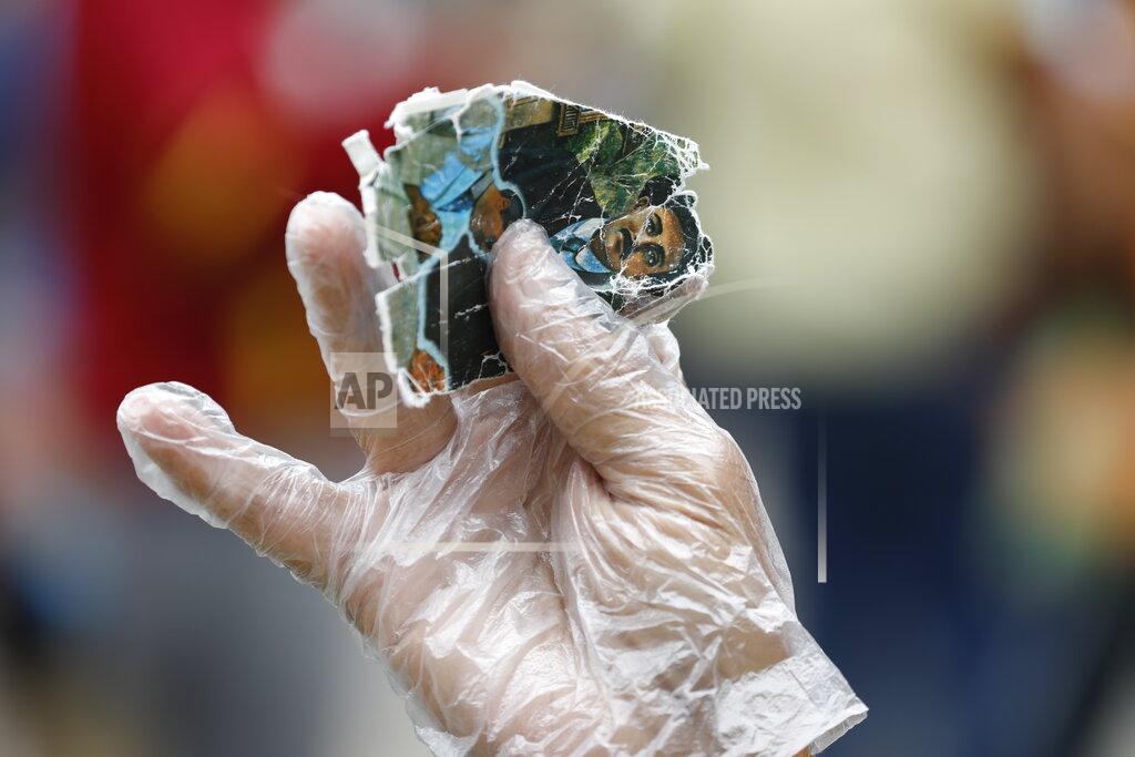 Ariana Cubillos A person wearing a plastic glove due to the COVID-19 pandemic holds up images of the late, Venezuelan Dr. Jose Gregorio Hernandez to be blessed by a priest with holy water outside the church associated with his remains to celebrate the day of his beatification ceremony in La Candelaria neighborhood of Caracas, Venezuela, Friday, April 30, 2021. Known as the "doctor of the poor," Hernandez is being beatified by the Catholic church, a step towards sainthood. (AP Photo/Ariana Cubillos)