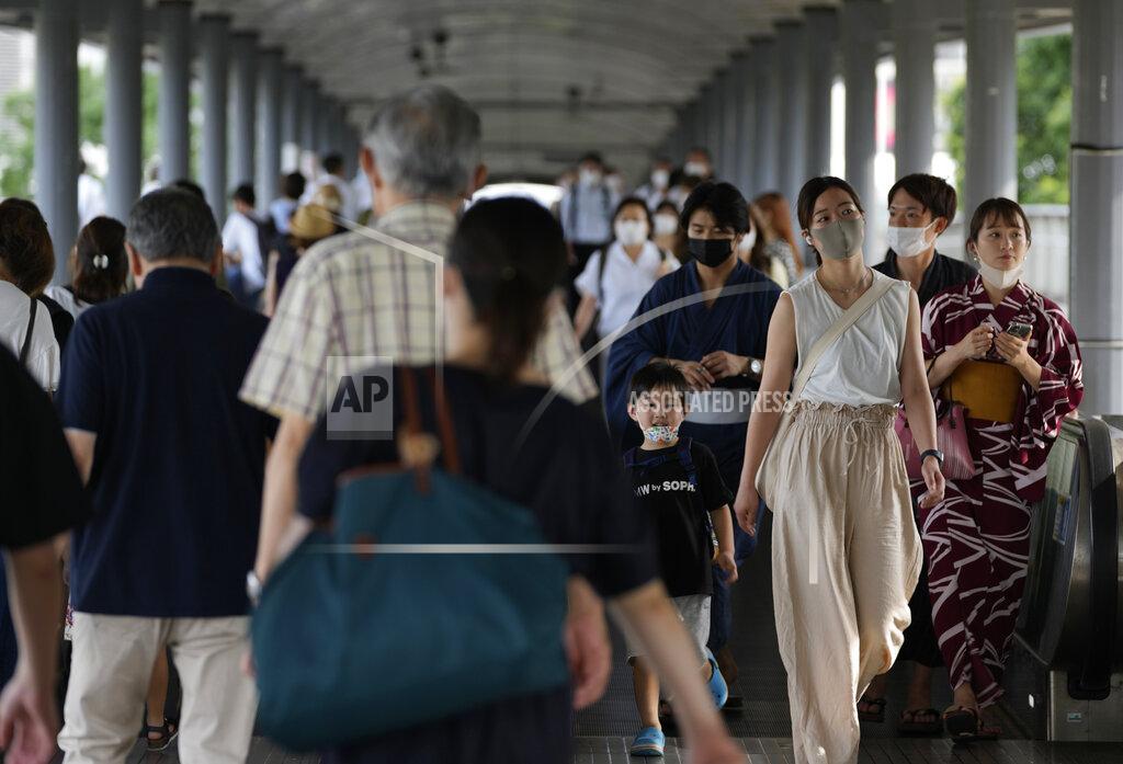Kiichiro Sato People wearing protective masks pass through a pedestrian bridge Friday, July 30, 2021, in Yokohama, south of Tokyo. Japan is set to expand the coronavirus state of emergency in Tokyo to neighboring prefectures including Saitama, Chiba and Kanagawa, where Yokohama is located, and the western city of Osaka as infections surge to new highs while the capital hosts the Olympics. (AP Photo/Kiichiro Sato)