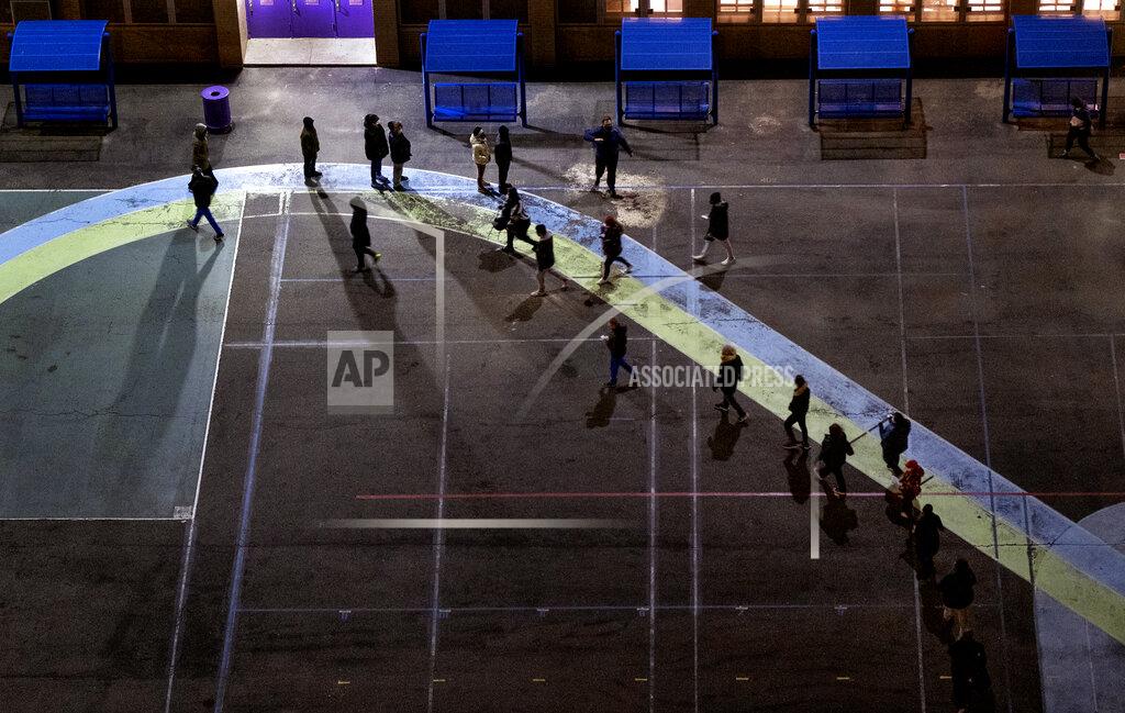 People line up on a playground before the door of a polling place opened at an elementary school in the Manhattan borough in New York Tuesday, Nov. 3, 2020. (AP Photo/Craig Ruttle)