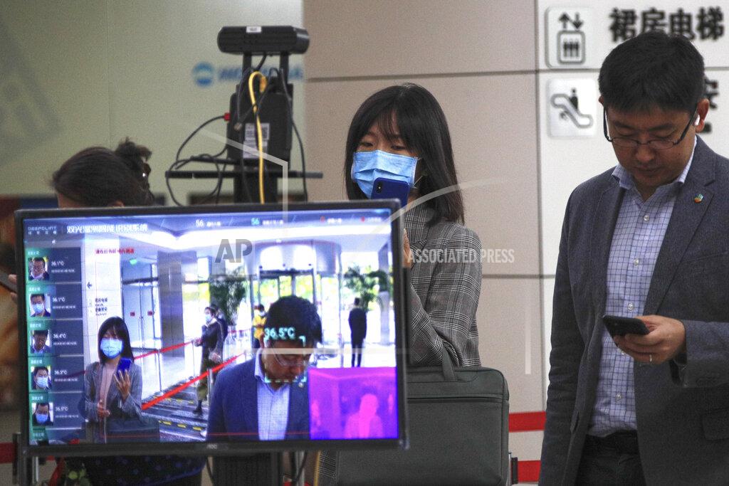 Andy Wong A monitor shows the temperature of people as they use their smartphones to scan their health code to help curb the spread of the coronavirus while entering an office building in Beijing, Thursday, Oct. 15, 2020. (AP Photo/Andy Wong)