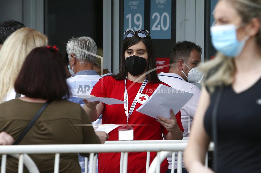 Boris Grdanoski A Red Cross volunteer hands people papers before entering the COVID-19 vaccination center, at A1 Arena in Skopje, North Macedonia, on Tuesday, May 4, 2021. The European Union started delivering EU-funded coronavirus vaccines Tuesday to the Balkans, a region that wants to join the 27-nation bloc but where China and Russia have already been supplying the much-needed shots and making political gains. (AP Photo/Boris Grdanoski)