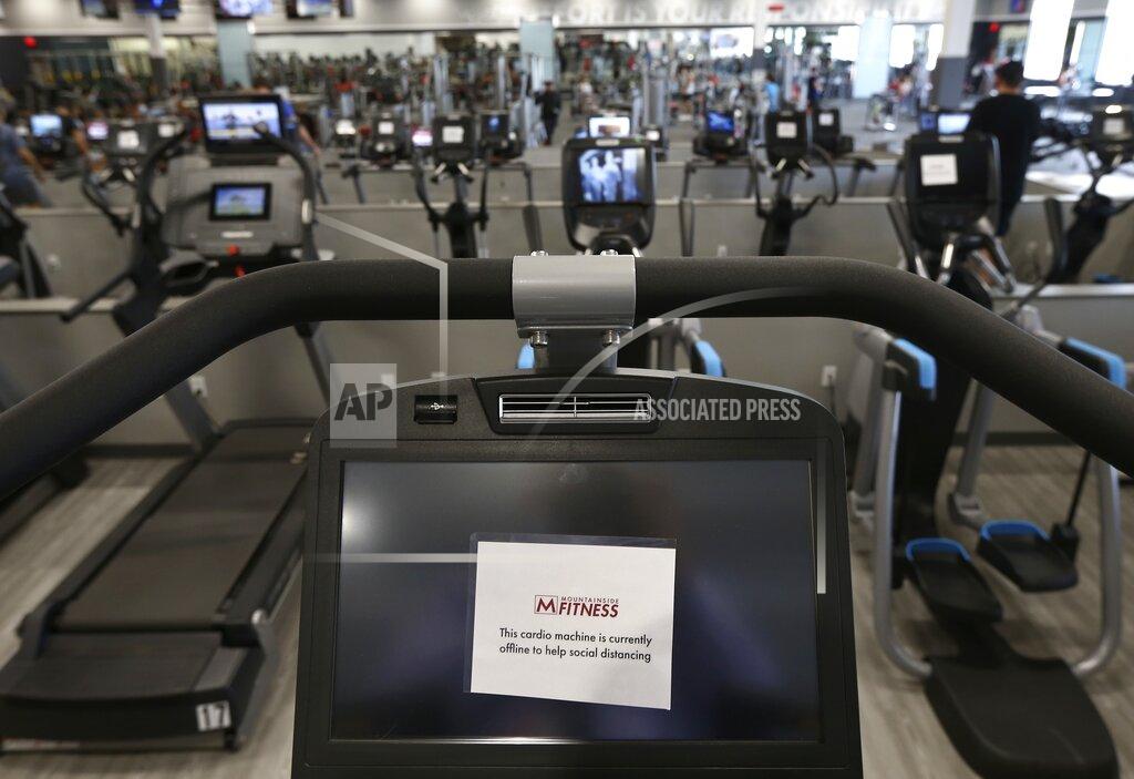 FILE - This July 2, 2020 file photo shows some gym equipment machines are turned off so clients can physically distance at Mountainside Fitness in Phoenix. Arizona Gov. Doug Ducey has lifted capacity restrictions at gyms, restaurants, and other businesses. Ducey cited lower COVID-19 cases and increased vaccination as he eases up on the pandemic restrictions that have upended life for nearly a year. Ducey announced the changes Friday, March 5, 2021, citing declining COVID-19 cases and the rollout of the vaccine. (AP Photo/Ross D. Franklin, File)