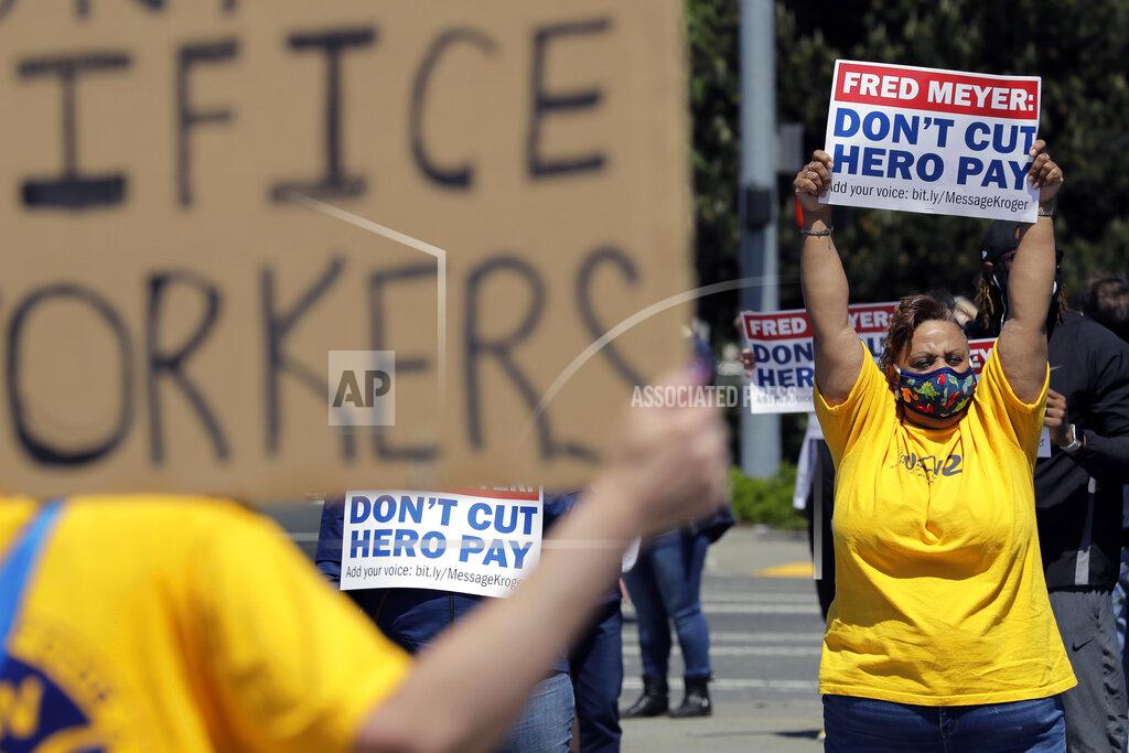 Ted S. Warren Members and supporters of the United Food and Commercial Workers International Union take part in a protest outside the Fred Meyer grocery store in Burien, Wash., against Fred Meyer's parent company Kroger, Friday, May 15, 2020. Kroger officials have said they are ending the additional $2 hourly "hero pay" bonus that had been paid to workers since late March during the coronavirus pandemic. The company said Friday it will now offer one-time bonus payments of $400 and $200 for full- and part-time employees to be paid in two installments. (AP Photo/Ted S. Warren)