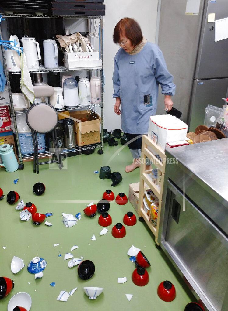 Tomomi Miura A landlady of a Japanese style hotel stands near damaged bowls following an earthquake in Minamisoma, Fukushima prefecture, northeastern Japan Saturday, Feb. 13, 2021. The Japan Meteorological Agency says a strong earthquake has hit off the coast of northeastern Japan, shaking Fukushima, Miyagi and other areas. (Tomomi Miura/Kyodo News via AP)
