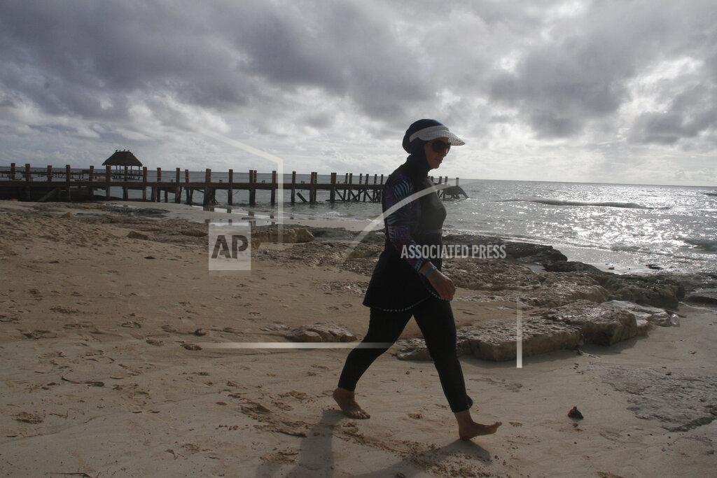 Zena Koudsi, from Charlotte, North Carolina, walks on the beach near Playa del Carmen, Mexico before Hurricane Delta arrives, early Tuesday, Oct. 6, 2020. Hurricane Delta rapidly intensified into a Category 2 hurricane Tuesday on a course to hammer southeastern Mexico and then grow to a potentially catastrophic Category 4 on approach to the U.S. Gulf Coast this week. (AP Photo/Tomas Stargardter)