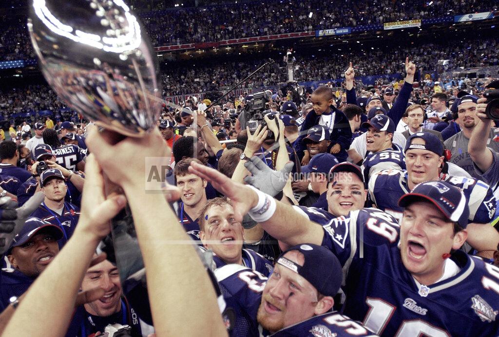 David J. Phillip FILE - In this Feb. 3, 2002, file photo, New England Patriots players reach out to touch the Vince Lombardi Trophy after the Patriots defeated the St. Louis Rams 20-17 to win NFL football Super Bowl 36 in New Orleans. A pair of Super Bowl winning teams that launched dynasties in San Francisco and New England highlighted the list of the NFL's greatest teams, numbers 31-100. Coming in at No. 31 were the 1981 San Francisco 49ers led by coach Bill Walsh and quarterback Joe Montana. The Patriots won a surprise title in 2001 after the untested Brady took over from the injured Drew Bledsoe early in the season. New England needed a favorable ruling and dramatic kick by Adam Vinatieri to win the "Tuck Rule" game against Oakland, won at Pittsburgh in the AFC championship game and slowed down the dynamic Rams offense for the franchise's first title. That team ranked 51st. (AP Photo/David J. Philli, File)
