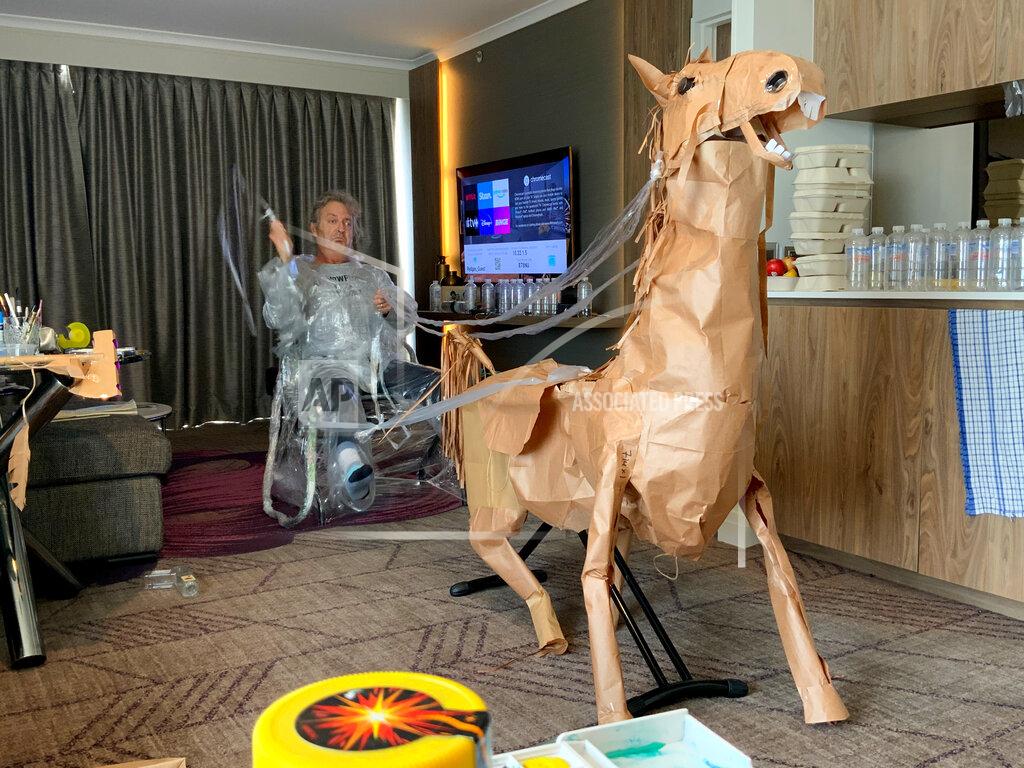 David Marriott CORRECTS NAME - David Marriott poses with his paper horse Russel in his hotel room in Brisbane, Australia, April 6, 2021. While in quarantine inside his Brisbane hotel room, the art director was bored and started making a cowboy outfit from the paper bags his meals were being delivered in. His project expanded to include a horse and a clingfilm villain that he has daily adventures with, in images that have gained a huge online following. (David Marriott via AP)