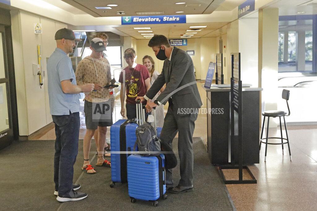 Rick Bowmer In this May 27, 2020, photo, Logan Morrison, 18, right, a missionary from The Church of Jesus Christ of Latter-day Saints, says goodbye to his family at Salt Lake City International Airport before leaving on his mission to St. Louis. After hastily bringing home 26,000 young men and women who were serving in foreign countries, the faith has begun sending many of them out again in their home countries with a new focus on online work that could stick even when the pandemic is over, church officials told The Associated Press. (AP Photo/Rick Bowmer)