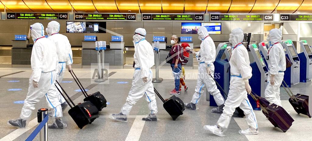 Keith Birmingham FILE - In this Nov. 17, 2020, file photo, a woman, accompanied by a child, looks over as an airline crew wearing full personal protective equipment against COVID-19, walks through the international terminal at Los Angeles International Airport in Los Angeles. Now, in early May 2021, California has the lowest coronavirus case rate in the country. (Keith Birmingham/The Orange County Register via AP, File)