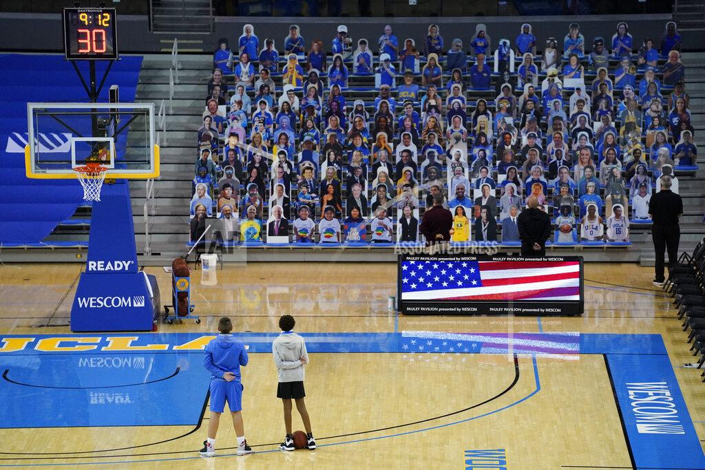 Ashley Landis Two ball boys stand on the court, facing cardboard cutouts of fans as the national anthem is played before an NCAA college basketball game between Arizona State and UCLA on Saturday, Feb. 20, 2021, in Los Angeles. (AP Photo/Ashley Landis)