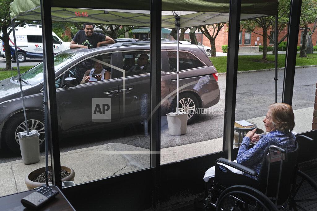 Seth Wenig FILE - Gloria DeSoto, 92, right, visits with her family, in their car, from a window of the Hebrew Home at Riverdale, where she lives, in New York, Thursday, June 11, 2020. A focus on the elderly at the start of the nation's vaccination campaign helped protect nursing homes that were ravaged at the height of the U.S. coronavirus outbreak, but they are far from in the clear. New outbreaks, often traced to infected staff members, are still occurring in long-term care centers across the country, causing continued havoc for visitation policies. (AP Photo/Seth Wenig)