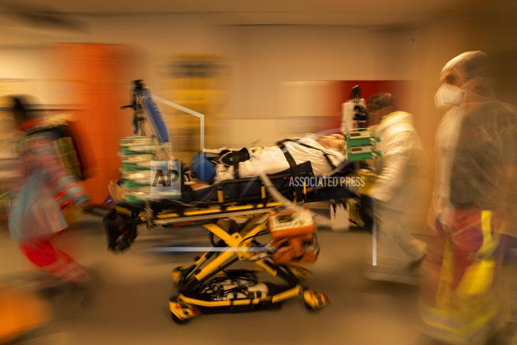 Francisco Seco FILE- In this April 14, 2021, file photo, medical personnel wearing protective equipment wheel a bed with a coronavirus patient in critical condition as they prepare to transfer the patient by ambulance to a hospital in Aachen, Germany, at the MontLegia CHC hospital in Liege, Belgium. (AP Photo/Francisco Seco, File)