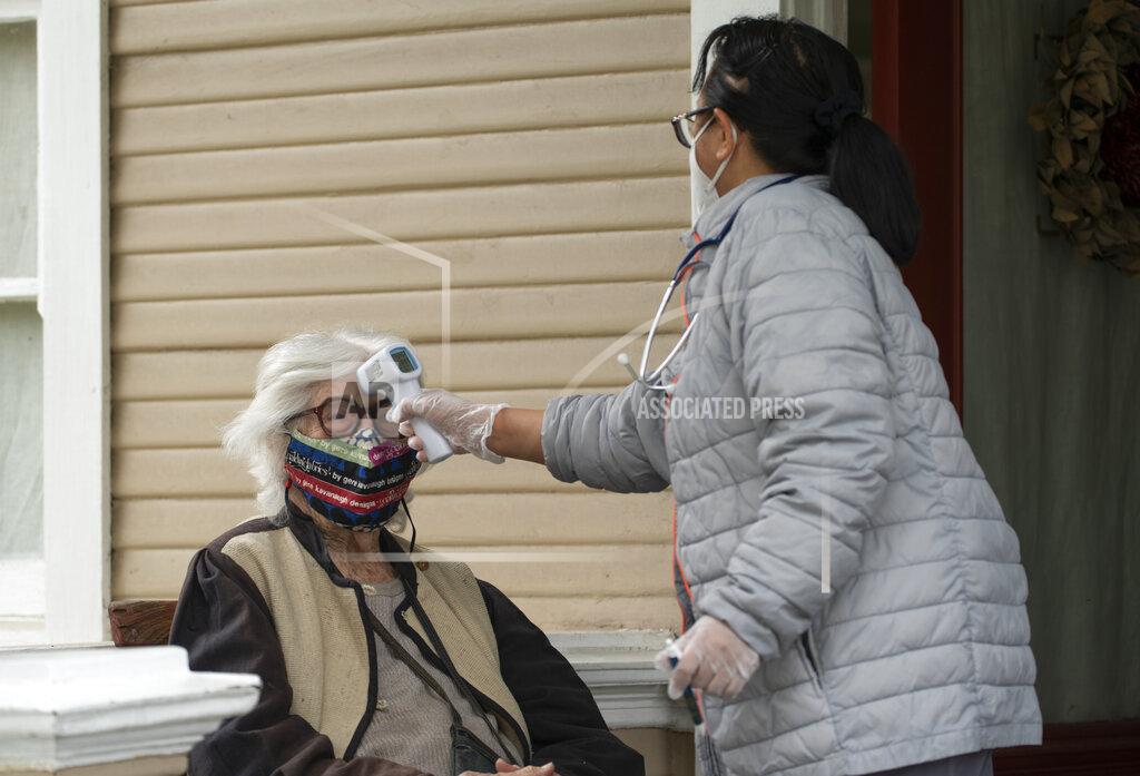Damian Dovarganes Designer Gere Kavanaugh, left, wears a face mask of her design in the Echo Park neighborhood of Los Angeles, Monday, May 17, 2021. At right, Silver Age Home Health licensed vocational nurse Daisy Cabaluna monitors her temperature during a weekly outdoors visit at her home. California is keeping its rules for wearing face masks in place until the state more broadly lifts its pandemic restrictions on June 15. (AP Photo/Damian Dovarganes)