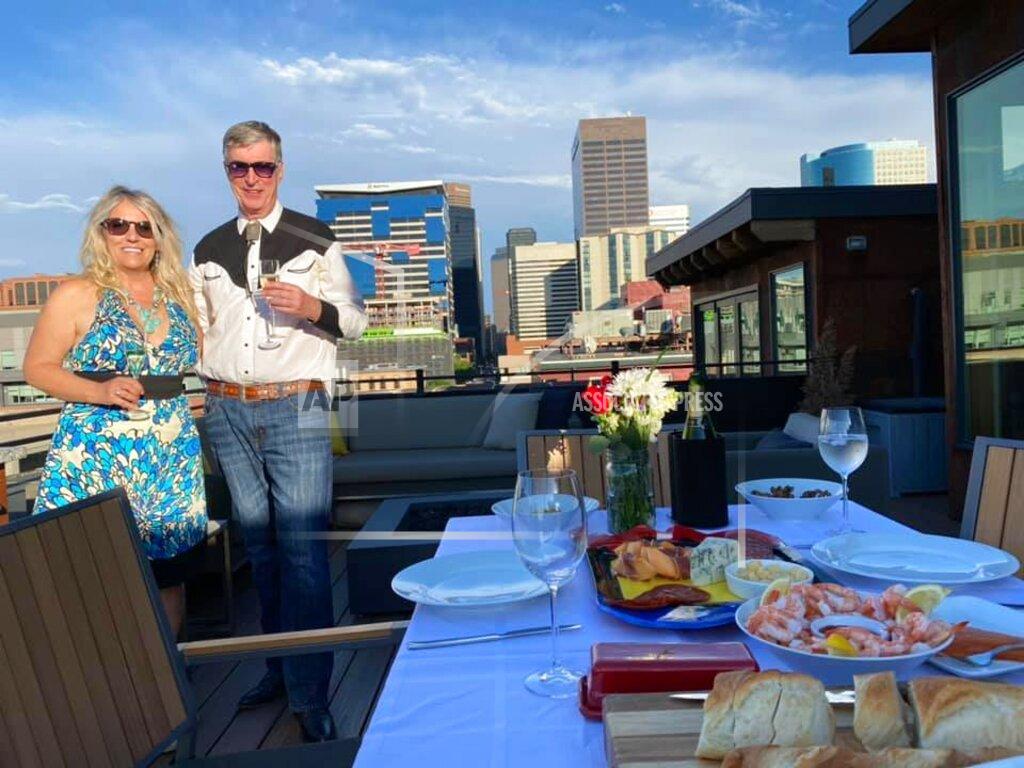 Peter Batty This July 3, 2020 image provided by Peter Batty shows him and his wife celebrating their anniversary and the opening night of the Santa Fe Opera on their balcony in Denver, Colorado. The famed opera is offering a series of virtual performances after being forced to cancel the 2020 season due to the coronavirus pandemic. The Saturday night events are meant to celebrate the five originally-scheduled operas that would have been performed this summer. (Peter Batty via AP)