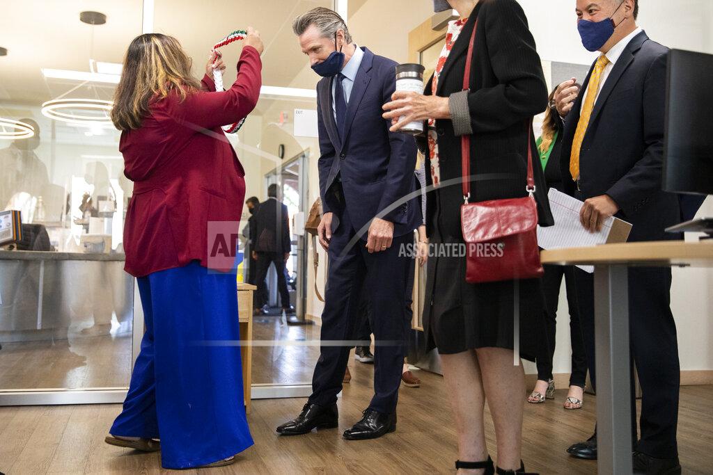 Jessica Christian Unity Council Associate Director of Economic Development Tiffany Lacsado gifts Gov. Gavin Newsom with a lanyard in the colors of the Mexican flag while on a tour of Unity Council career center in the Fruitvale neighborhood of Oakland, Calif., on Monday, May 10, 2021. (Jessica Christian/San Francisco Chronicle via AP)