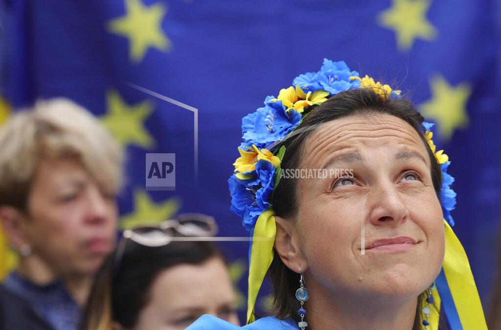 Olivier Matthys A protestor wears a flower headband in the Ukraine colors as she participates in a demonstration in support of Ukraine outside of an EU summit in Brussels, Thursday, June 23, 2022. European Union leaders are expected to approve Thursday a proposal to grant Ukraine a EU candidate status, a first step on the long toward membership. (AP Photo/Olivier Matthys)