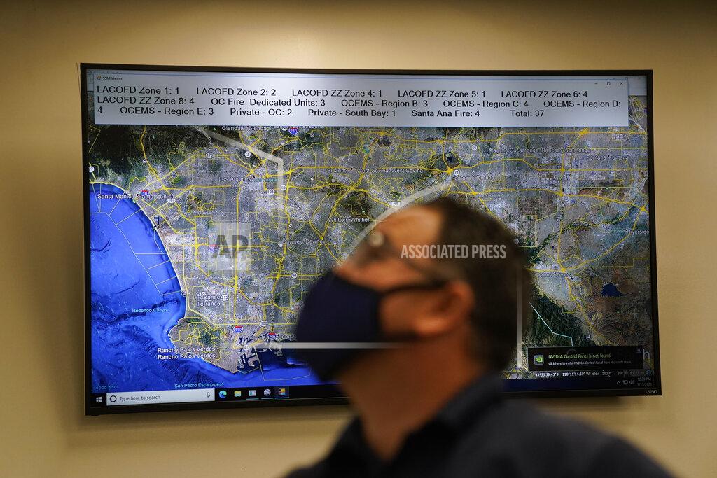 Jae C. Hong Dispatch Supervisor Erick Aguilar stands in front of a screen showing the map of Los Angeles County while working in Care Ambulance Service's communication center in Santa Fe Springs, Calif., Saturday, Jan. 9, 2021. Dispatchers play chess with ambulances all day. When one gets stuck at a hospital for eight, 10 or 12 hours, the dispatchers must reposition the others to cover its area. When an EMT reports a positive COVID-19 test, the dispatchers must find a way to cover the ambulance's calls if the whole crew must quarantine. (AP Photo/Jae C. Hong)