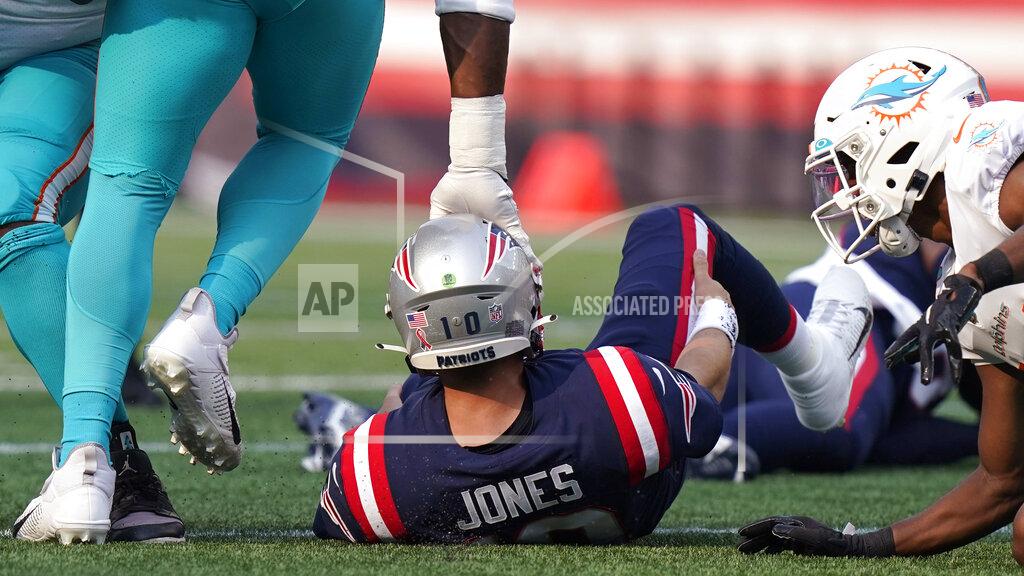 Steven Senne New England Patriots quarterback Mac Jones is tapped on the helmet after being sacked by the Miami Dolphins during the first half of an NFL football game, Sunday, Sept. 12, 2021, in Foxborough, Mass. (AP Photo/Steven Senne)