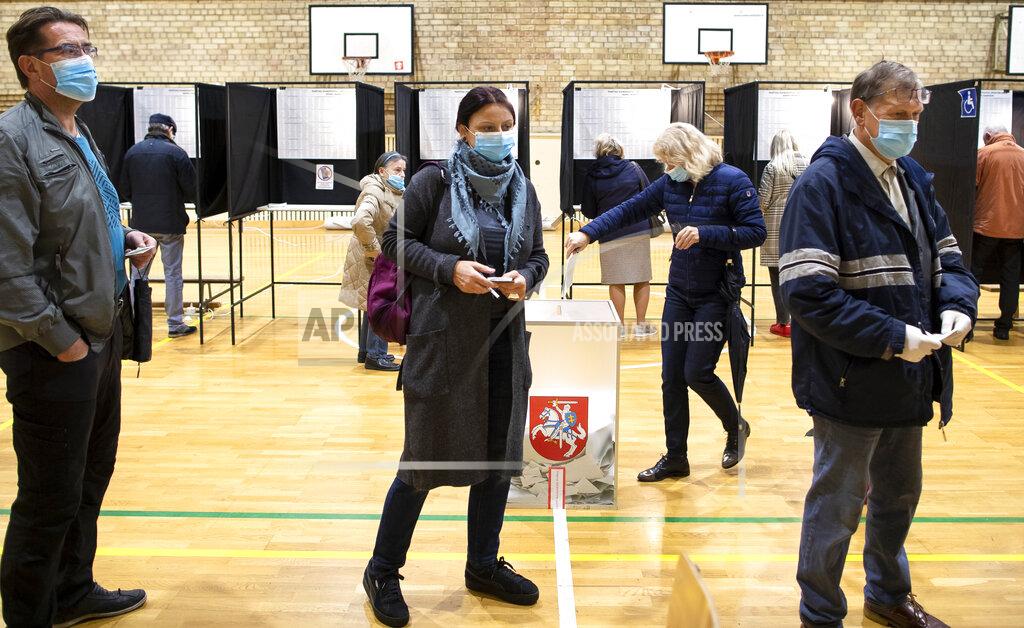 Mindaugas Kulbis People wear face masks to protect against coronavirus as they queue to cast their ballots during the parliamentary elections in Vilnius, Lithuania, Sunday, Oct. 11, 2020. Polls opened Sunday for the first round of national election in Lithuania, where voters will renew the 141-seat parliament and the ruling four-party coalition is widely expected to face a stiff challenge from the opposition to remain in office. (AP Photo/Mindaugas Kulbis)