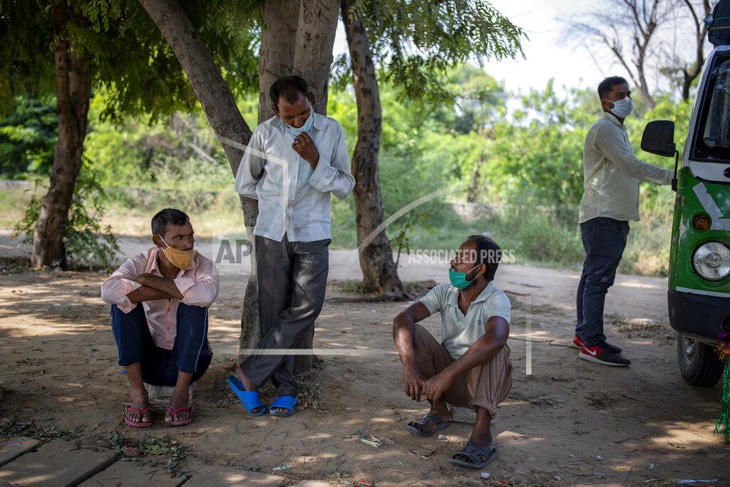 Altaf Qadri Migrant workers Ram Ratan, center standing, and Mansoor Ansari, seated right, talk sitting by the side of a road as they look for jobs in Manesar, India, Tuesday, Sept. 22, 2020. “There is almost no work,” said Ratan, 46, who was working in a printing company before he returned to his home village in April. Ansari and Ratan are among hundreds of workers who wait every day on what is called a “labor roundabout,” in an industrial area, hoping to get picked up by employers. Before the pandemic lockdown, Ansari had a steady job at a garment factory in the industrial town of Manesar near New Delhi, earning $200 a month, he said. (AP Photo/Altaf Qadri)