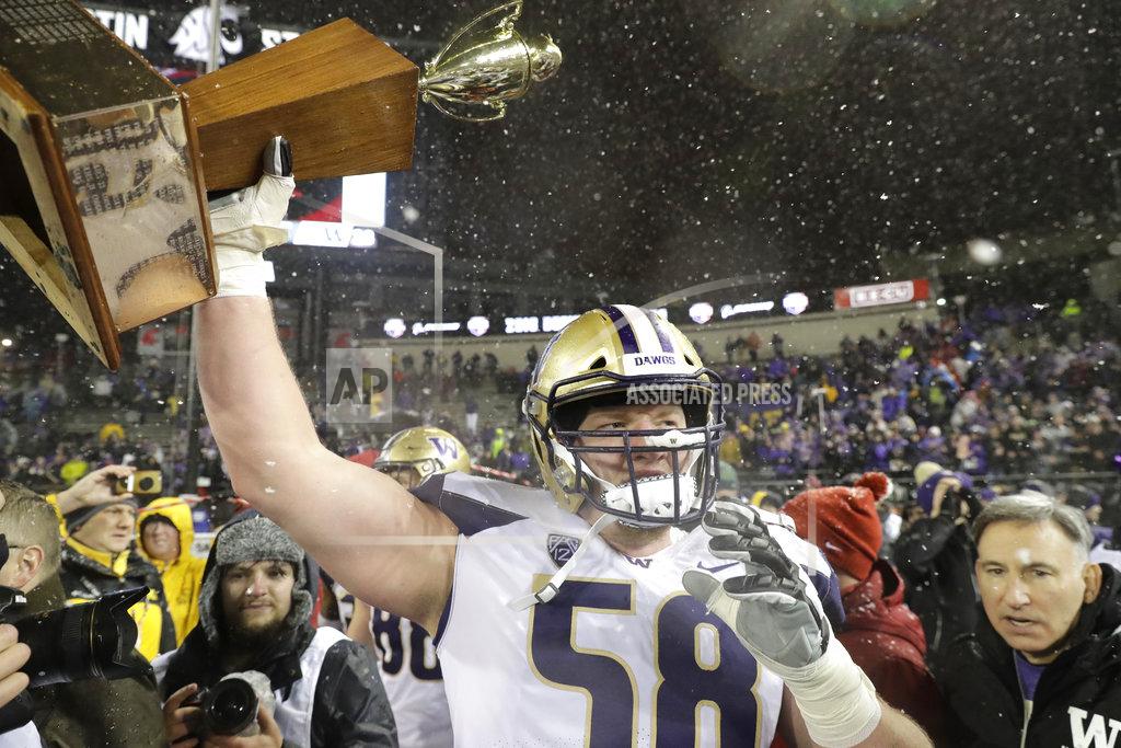 Ted S. Warren Washington offensive lineman Kaleb McGary holds up the Apple Cup trophy after Washington defeated Washington State 28-15 in an NCAA college football game, Friday, Nov. 23, 2018, in Pullman, Wash. (AP Photo/Ted S. Warren)