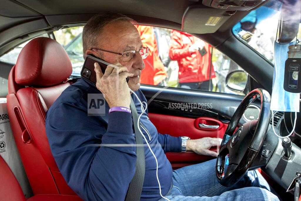 Robert F. Bukaty Former Gov. Paul LePage, sitting in a Lexus SC 430, uses his cell phone to address protesters rallying against the executive orders by Gov. Janet Mills to keep some Maine businesses closed to help prevent the spread of coronavirus, Saturday, May 16, 2020, in Augusta, Maine. His call was broadcast over speakers set up at the nearby rally. LePage, now a resident of Florida, stayed in his car parked near the rally. A speaker at the event said the former governor was quarantining. (AP Photo/Robert F. Bukaty)