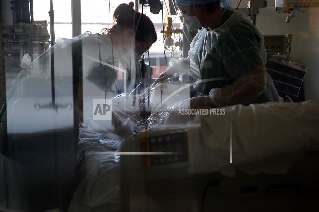 Medical workers tend to a patient affected with the COVID-19 in the Amiens Picardie hospital Tuesday, March 30, 2021 in Amiens, 160 km (100 miles) north of Paris. France is now facing a deadly new surge of the virus that is overwhelming many hospitals, as critics accuse the government of ignoring warning signs and favoring political concerns over public health. (AP Photo/Francois Mori)
