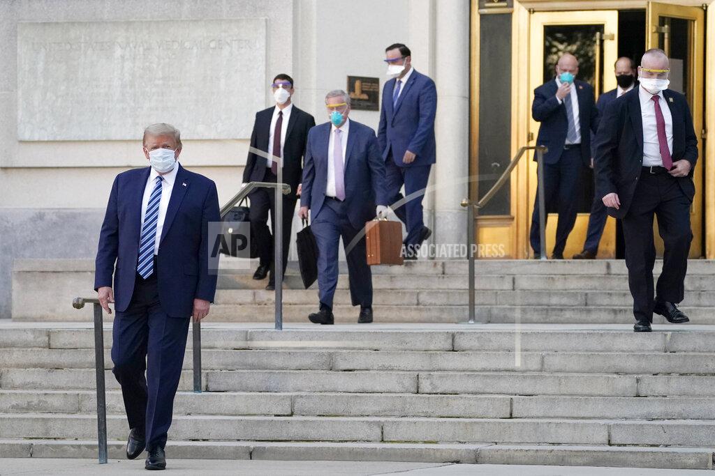 Evan Vucci President Donald Trump, left, walks out of Walter Reed National Military Medical Center to return to the White House after receiving treatments for covid-19, Monday, Oct. 5, 2020, in Bethesda, Md. (AP Photo/Evan Vucci)
