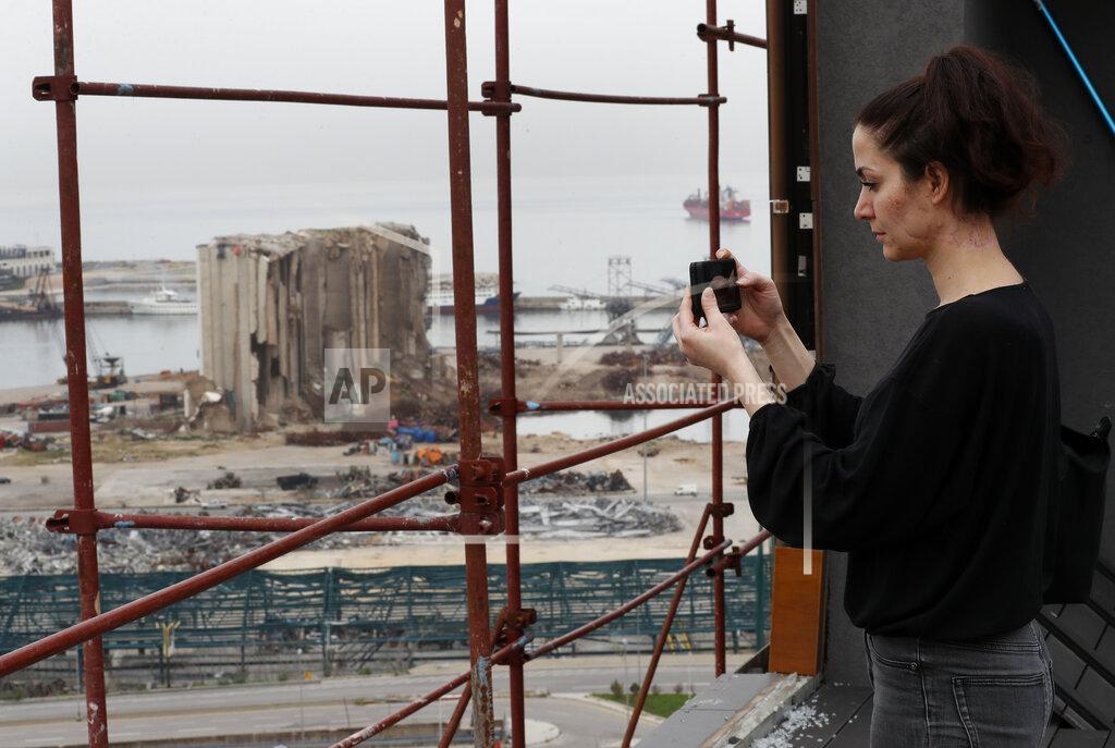 Hussein Malla Joana Dagher, 33, who lost her memory for two full months from the trauma she suffered in the massive August explosion at the Beirut port, including a cerebral contusion and brain lesions, takes pictures of the explosion scene from her damaged apartment rooftop, in Beirut, Lebanon, Wednesday, Jan. 27, 2021. The mental health impact of the Beirut explosion that killed more than 200 and wounded more than 6,000 continues to lay its heavy weight on those who managed to survive the day. (AP Photo/Hussein Malla)