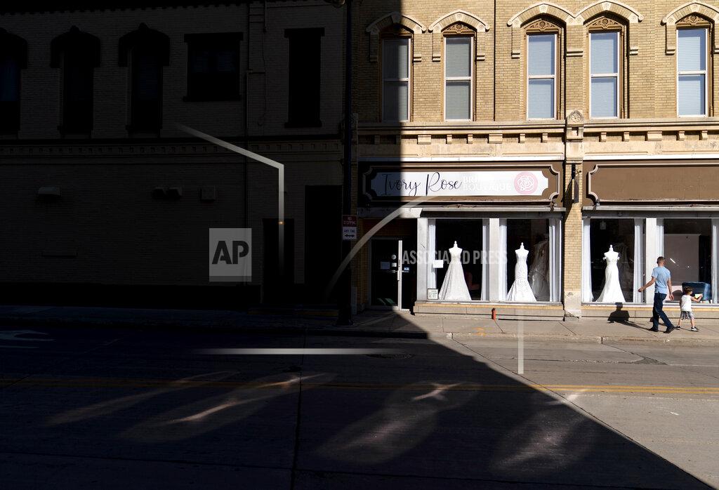 David Goldman A father and son walk past a wedding gown shop in Appleton, Wis., Aug. 19, 2020. The downtown had been evolving as young parents moved back to Wisconsin from Minneapolis and Chicago, just to raise kids and open a business. Restaurants and boutiques popped up along College Avenue, catering to the professors and students at Lawrence University. Then the pandemic struck. (AP Photo/David Goldman)