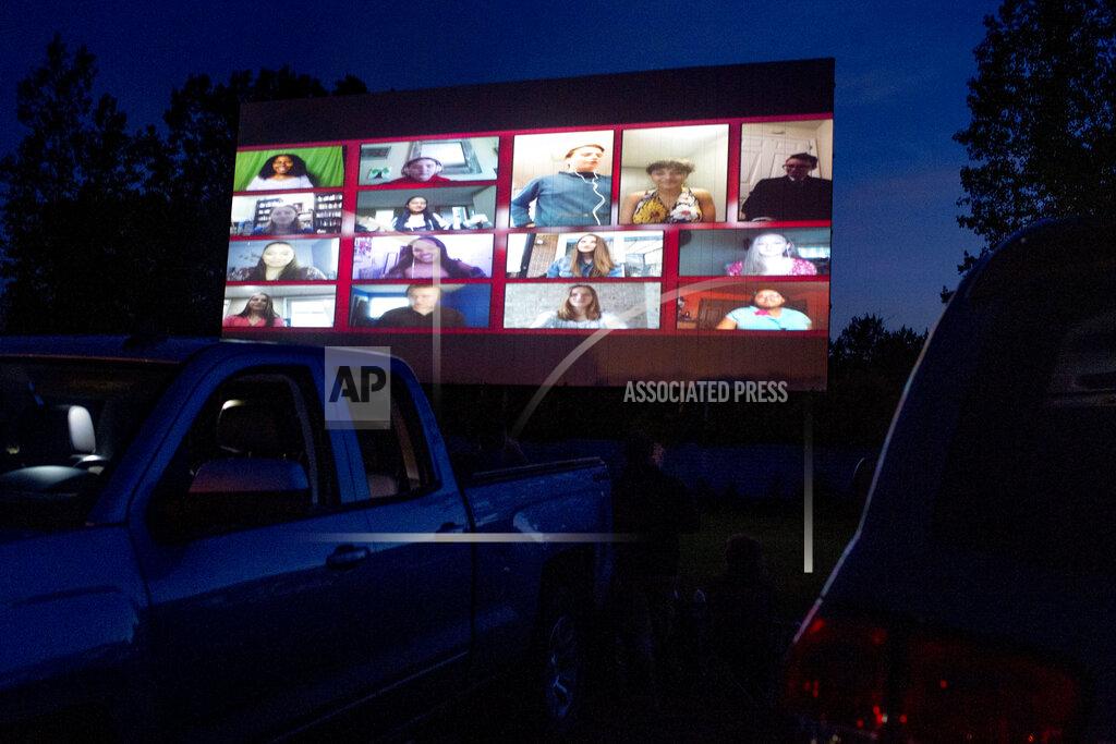 Jake May An outdoor movie screen showcases 15 choir students singing the class song, One Republic's "I Lived," during a 90-minute graduation film as about 650 Grand Blanc High School seniors attend a commencement ceremony Thursday, June 4, 2020, at a drive-in movie theater in Mundy Township, Mich. The school district switched to the location for the commencement ceremony to provide a safe space for social distancing due to the COVID-19 pandemic. (Jake May/The Flint Journal via AP)