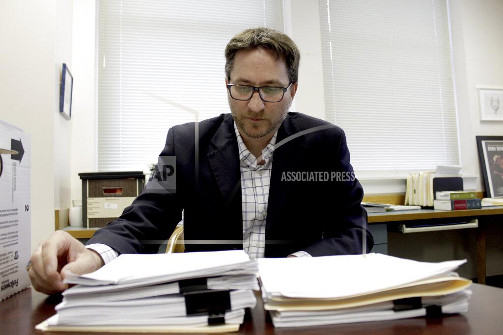 Gillian Flaccus FILE - Carl Macpherson, executive director at Metropolitan Public Defender, examines the file in a double murder case that was recently pushed back for trial in his office in Portland, Ore., on May 5, 2022. (AP Photo/Gillian Flaccus, File)
